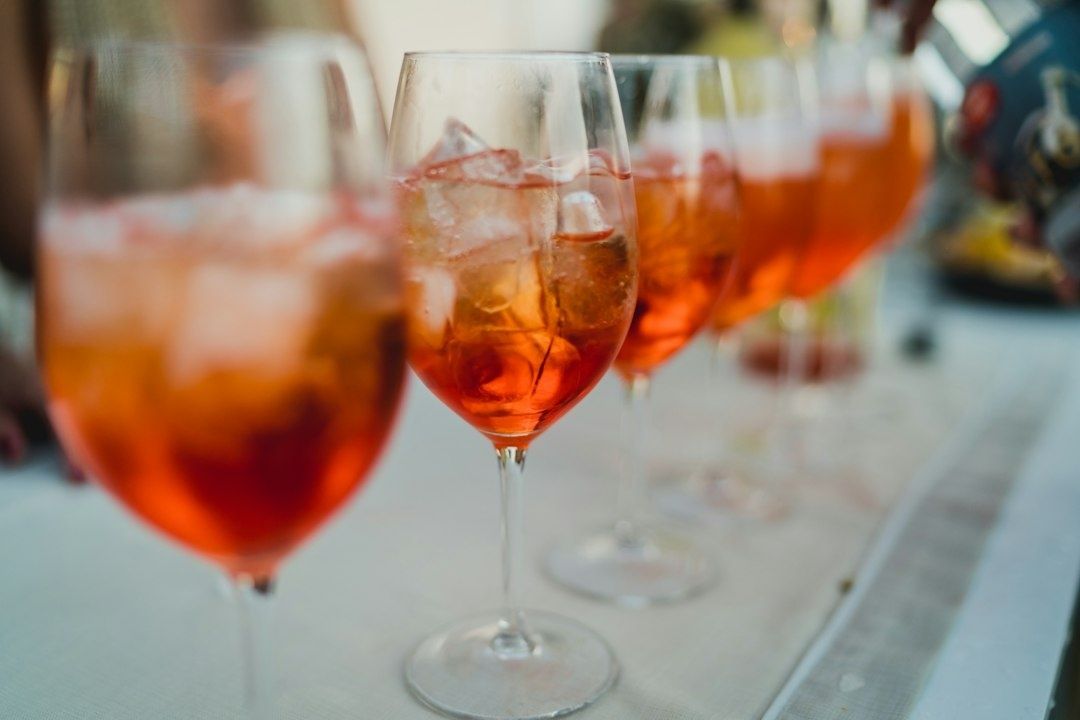 Kolme oranssia aperitiivicocktailia viinilaseissa pöydällä